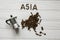 Map of the Asia made of roasted coffee beans laying on white wooden textured background