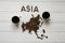 Map of the Asia made of roasted coffee beans laying on white wooden textured background with two cups of coffee