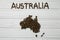 Map of the Australia made of roasted coffee beans laying on white wooden textured background