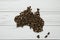 Map of the Australia made of roasted coffee beans laying on white wooden textured background