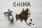 Map of the China made of roasted coffee beans laying on white wooden textured background with coffee maker