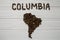 Map of the Columbia made of roasted coffee beans laying on white wooden textured background