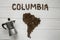 Map of the Columbia made of roasted coffee beans laying on white wooden textured background with coffee maker