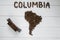 Map of the Columbia made of roasted coffee beans laying on white wooden textured background toy train