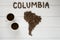 Map of the Columbia made of roasted coffee beans laying on white wooden textured background with two coffee cups