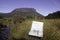 A map and a compass on a buttongrass plain in front of a rocky escarpment on Tasmania Australia`s Overland Track