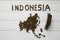 Map of the Indonesia made of roasted coffee beans laying on white wooden textured background with toy train