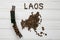 Map of the Laos made of roasted coffee beans laying on white wooden textured background with toy train