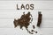 Map of the Laos made of roasted coffee beans laying on white wooden textured background with toy train