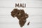 Map of the Mali made of roasted coffee beans laying on white wooden textured background