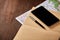 Map, notebook, pen and black telephone on the brown wooden background.