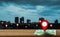 Map pointer icon placed on a wooden table, background is a view of the city and skyscrapers at sunset, With the concept of using