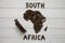 Map of the South Africa made of roasted coffee beans laying on white wooden textured background with toy train