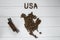 Map of the USA made of roasted coffee beans laying on white wooden textured background with toy train