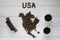 Map of the USA made of roasted coffee beans laying on white wooden textured background with two cups of coffee and toy train