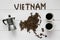 Map of the Vietnam made of roasted coffee beans laying on white wooden textured background with cups of coffee and coffee maker