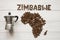 Map of the Zimbabwe made of roasted coffee beans laying on white wooden textured background with coffee maker