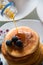 Maple syrup spilling on fresh homemade pancakes with blueberries, sweet tasty breakfast meal detail