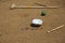 Marble balls on sand background. Croquet mallet. Playing children equipment.