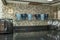 Marble countertop and tiled walls with a metal shelf filled with mugs