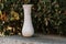 Marble empty vase on green leaves background outdoors