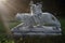 Marble sculpture of chinese tiger and warrior in a garden with green grass and sunset sun as background.