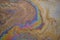 A marble texture of a rainbow spill of gasoline on a sidewalk in a puddle as a background