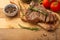 Marbled beef steak on a board with rosemary pepper, spices, and fresh vegetables, tomatoes and asparagus, artichoke, on a wooden