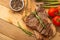 Marbled beef steak on a board with rosemary pepper, spices, and fresh vegetables, tomatoes and asparagus, artichoke, on a wooden