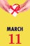 March 11th. Festive Vertical Calendar With Hands Holding White Gift Box With Red Ribbon And Calendar Date