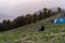 March 13th 2021 Nag tibba Uttarakhand India. A man sitting alone on a mountain nearby a camping tent during Sunset