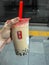 March 2019 - South Korea: Caucasian female hand holding a jumbo size black milk tea with pearls or bubble tea from Gong Cha