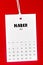 The March 2023 calendar page hanged on white rope  on Red background