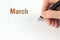 March. Month, Calendar month.The hand holds a black pen and writes the calendar date. Spring  , month of the year concept