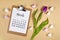 March month concept with clipboard with calendar sheet, purple tulip spring flower and hearst on cream colored background