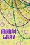 Mardi Gras beads in green, gold and purple hanging, draped in front of a yellow background.