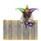 Mardi gras carnival pug dog with harlequin jester hat and venetian mask hanging on wooden fence