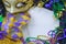 Mardis Gras border on marble background includes harlequin mask with green, gold and purple beads and matching fabrics.