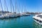 Marina Zeas in Piraeus, Greece. Many moored yachts. Reflection of boats, blue calm sea, city and sky background