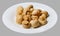 Marinated champignons on a white round plate. Light gray  background. Top side view.