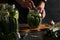 Marinated cucumbers with garlic, pepper and dill in a glass jars on dark background. Woman fills a jar with cucumbers, Closeup