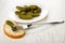 Marinated gherkin strung on fork on bread, plate with cucumbers on wooden table