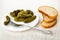 Marinated gherkin strung on fork in plate with cucumbers, pieces of bread on table