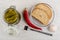 Marinated gherkins in glass jar, fork, garlic, chili peppers, bread in plate on table. Top view