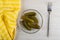 Marinated gherkins in transparent plate, napkin, fork on table. Top view