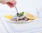 Marinated herring fillet on a white plate with lemon and onion. Served table and the traditional spring delicacy of the