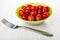 Marinated tomato cherry in bowl, fork on table