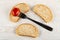 Marinated tomato strung on fork on piece of bread, bread on table. Top view