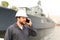 Marine captain talking by VHF walkie talkie near vessel in background.