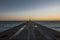 Marine concrete pier with crane at sunset.